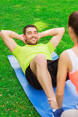 Image showing smiling man doing exercises on mat outdoors