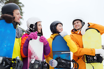 Image showing happy friends in helmets with snowboards talking