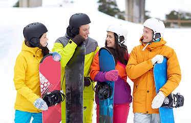 Image showing happy friends in helmets with snowboards talking