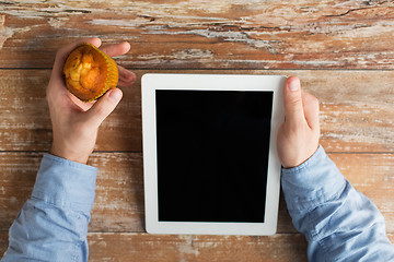 Image showing close up of male hands with tablet pc and muffin