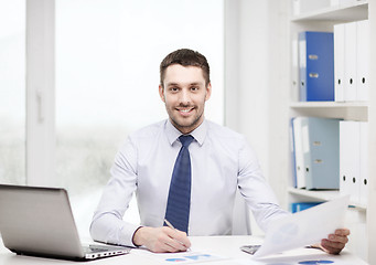 Image showing smiling businessman with laptop and documents