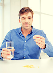 Image showing man at home showing lot of pills