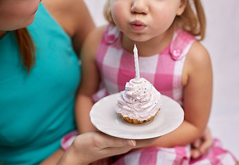 Image showing happy mother and girl blowing out cupcake candle