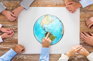 Image showing close up of hands with globe picture at table