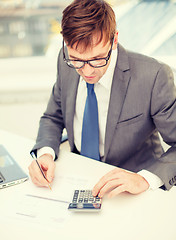 Image showing businessman with computer, papers and calculator