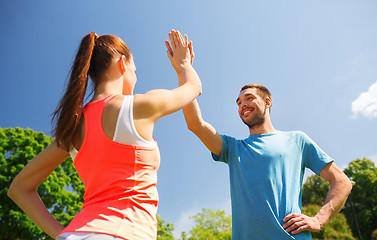 Image showing two smiling people making high five outdoors