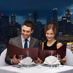 Image showing smiling couple with menus at restaurant