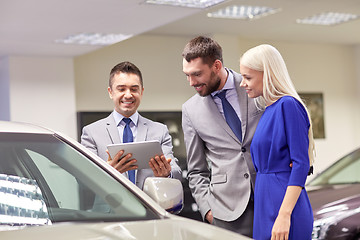 Image showing happy couple with car dealer in auto show or salon