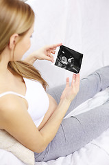 Image showing happy pregnant woman with ultrasound image at home