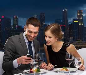 Image showing smiling couple with smartphone at restaurant