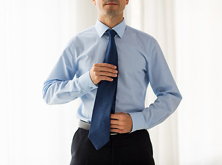 Image showing close up of man in shirt adjusting tie on neck