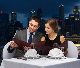 Image showing smiling couple with menus at restaurant