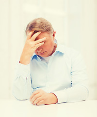 Image showing stressed old man holding head at home