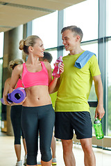 Image showing smiling couple with water bottles in gym