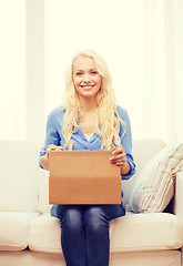 Image showing smiling young woman opening cardboard box