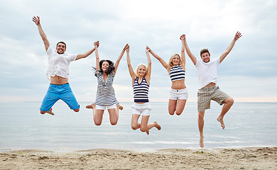 Image showing smiling friends in sunglasses walking on beach