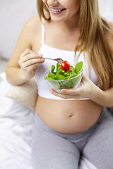 Image showing close up of pregnant woman eating salad from bowl 