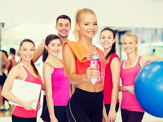 Image showing smiling sporty woman with water bottle and towel