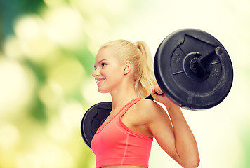 Image showing smiling sporty woman exercising with barbell