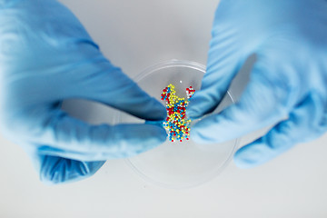 Image showing close up of scientist hands holding pill in lab