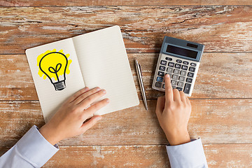 Image showing close up of hands with calculator and notebook