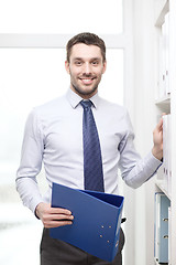 Image showing handsome businessman picking folder at office