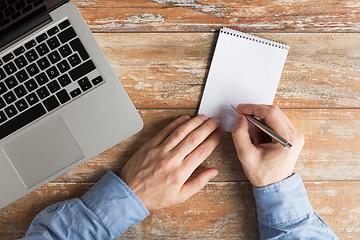 Image showing close up of male hands with laptop and notebook