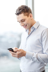 Image showing smiling businessman with smartphone in office