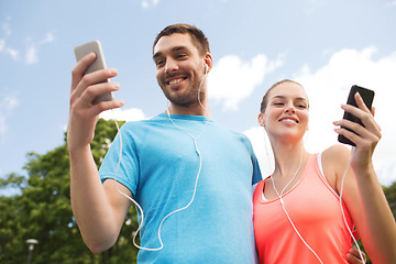 Image showing two smiling people with smartphones outdoors