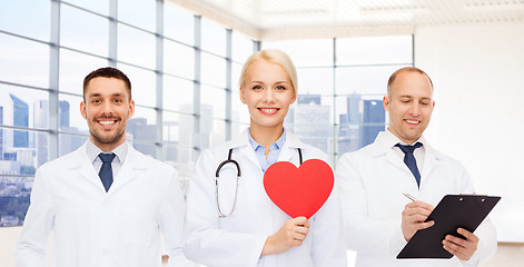 Image showing happy young doctors cardiologists with red heart