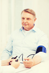 Image showing female doctor or nurse measuring blood pressure