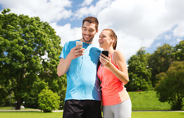 Image showing two smiling people with smartphones outdoors