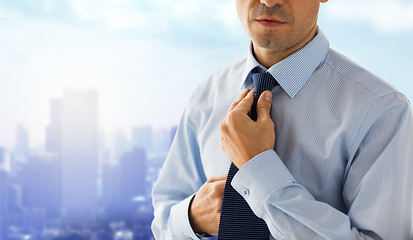 Image showing close up of man in shirt adjusting tie on neck