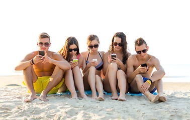 Image showing friends with smartphones on beach