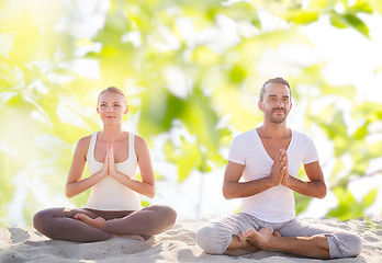 Image showing smiling couple making yoga exercises outdoors