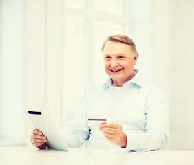 Image showing old man with tablet pc and credit card at home