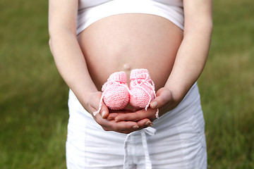 Image showing Pregnant woman outdoor with pink baby shoes in her hands