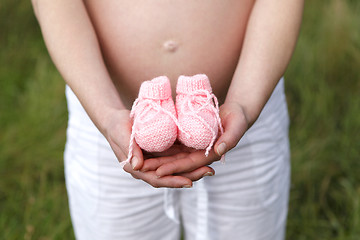 Image showing Pregnant woman outdoor with pink baby shoes in her hands