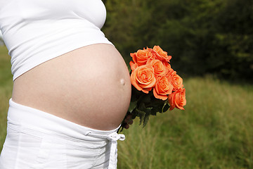 Image showing Pregnant woman outdoor with orange tulips in her hands