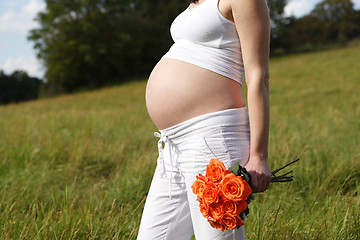 Image showing Pregnant woman outdoor with orange tulips in her hands