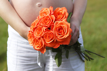 Image showing Pregnant woman outdoor with orange tulips in her hands