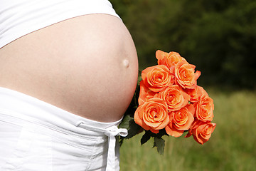 Image showing Pregnant woman outdoor with orange tulips in her hands
