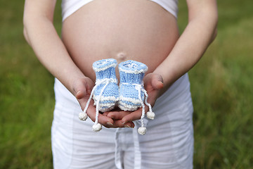 Image showing Pregnant woman outdoor with blue baby shoes in her hands