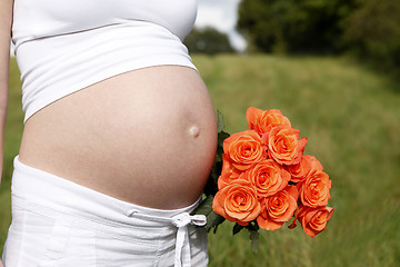 Image showing Pregnant woman outdoor with orange tulips in her hands