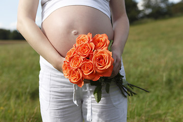 Image showing Pregnant woman outdoor with orange tulips in her hands