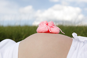 Image showing Pregnant woman with pink baby shoes on her belly