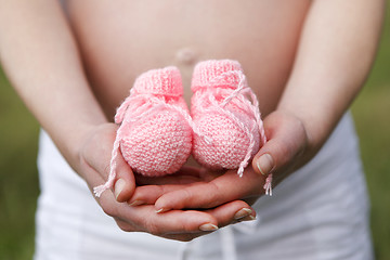 Image showing Pregnant woman outdoor with pink baby shoes in her hands