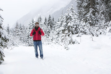 Image showing Young man with snow glasses hiking in wintry forest landscape