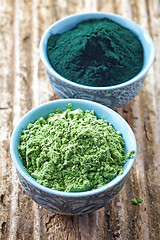 Image showing bowl of spirulina algae powder and wheat sprout powder on wooden