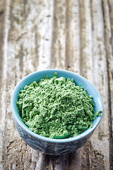 Image showing bowl of wheat sprouts powder on wooden background